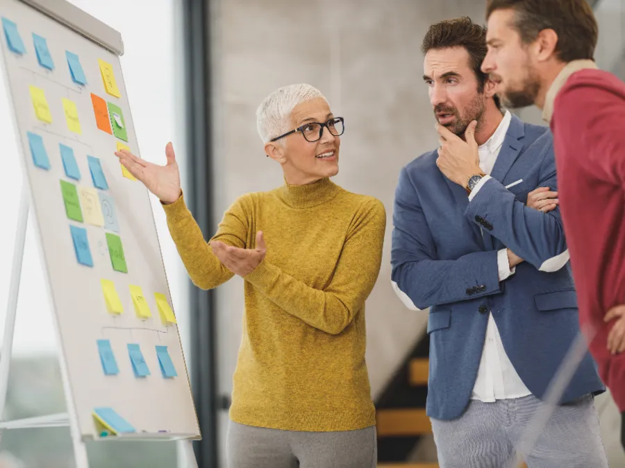 A woman leading a discussion at a whiteboard with colleagues