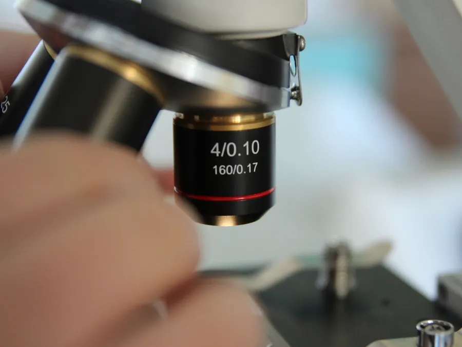 A researcher adjusting the objective lens of a microscope